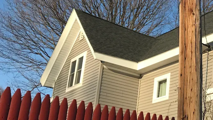 A house with a red fence and a wooden pole in front of it.