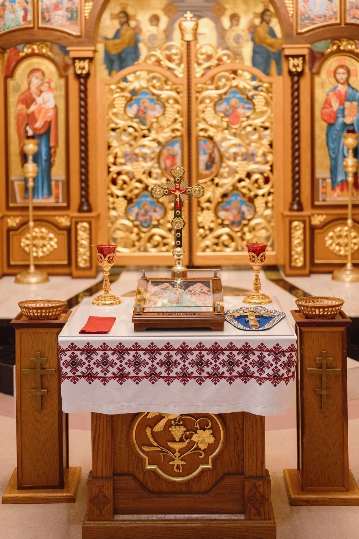 Ornate church altar with gold iconostasis, candles, and a white cloth-covered table
