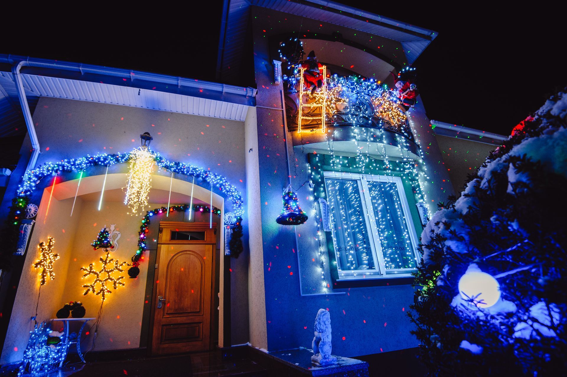 A house facade at night covered in bright, festive Christmas decorations, including string lights and a lighted snowflake. A house facade at night covered in bright, festive Christmas decorations, including string lights and a lighted snowflake.