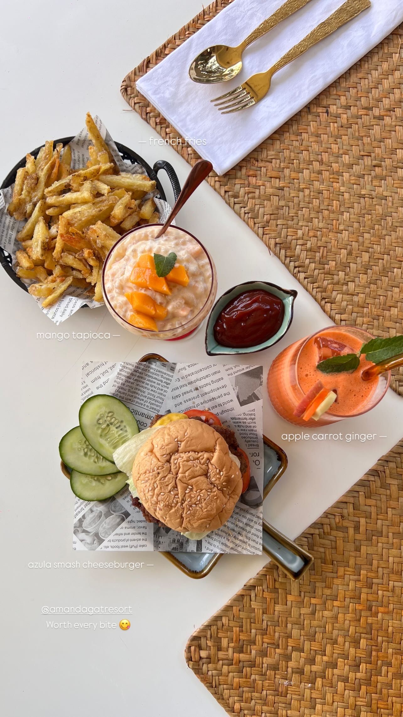 A bird's-eye view of a lunch spread featuring a burger with cucumber slices, french fries, a fruit bowl, and a drink.