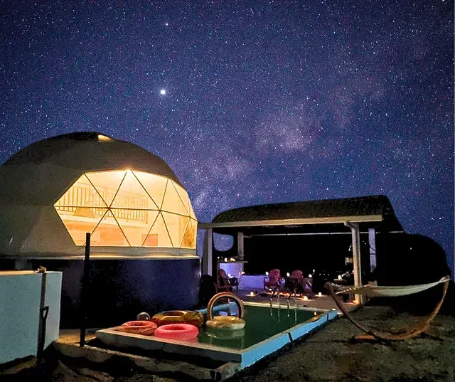 Geodesic dome glamping with a pool under a starry night sky.