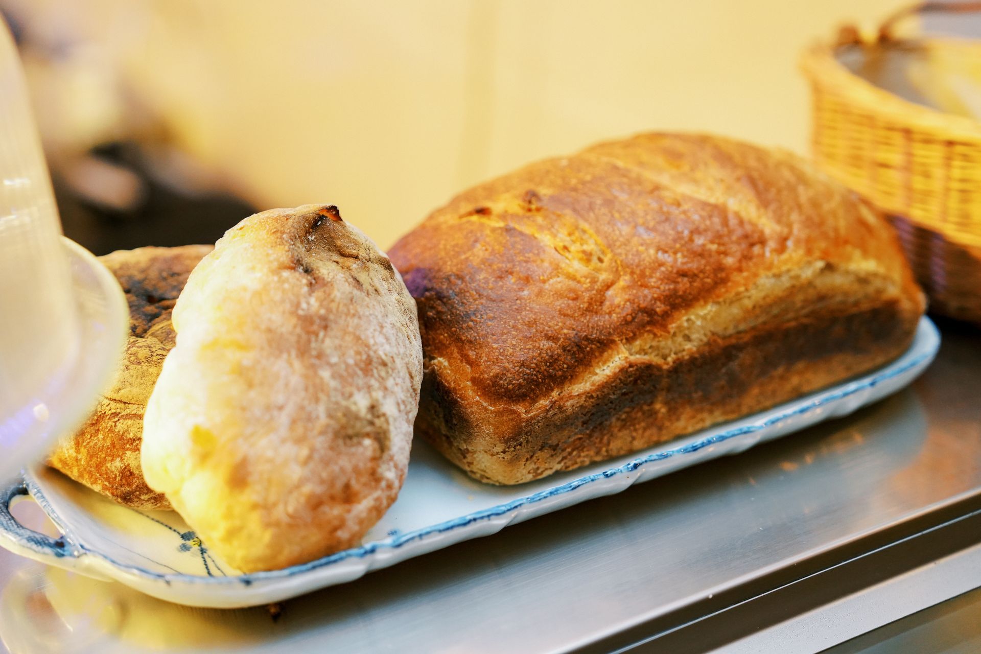 Bread loaves on a plate, with a rustic, golden crust and a wicker basket in the background.