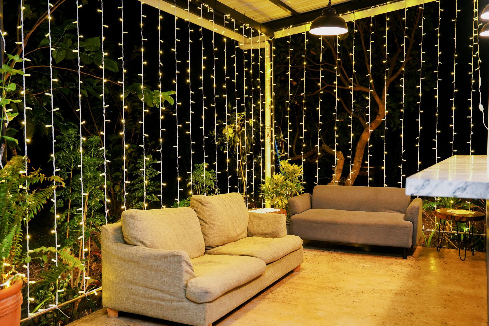 Outdoor seating area at night with string lights, two couches, and plants.