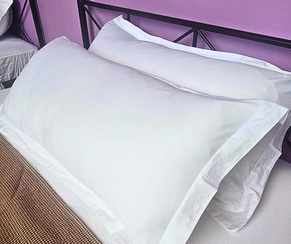 Two white pillows on a bed with a dark metal headboard and a brown patterned blanket.