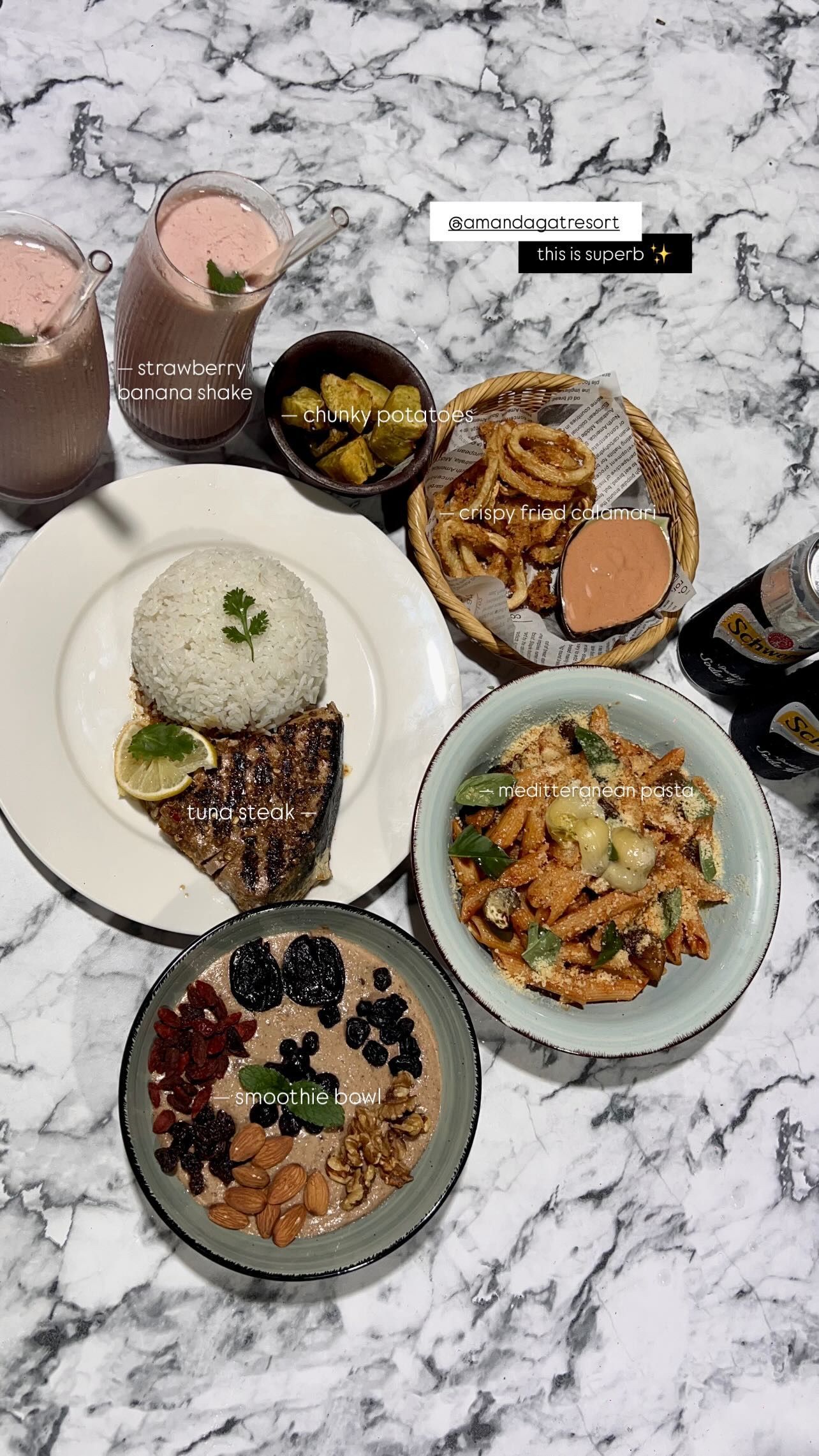 A marble tabletop filled with diverse dishes, including rice, pasta, onion rings, a smoothie bowl, and pink beverages.