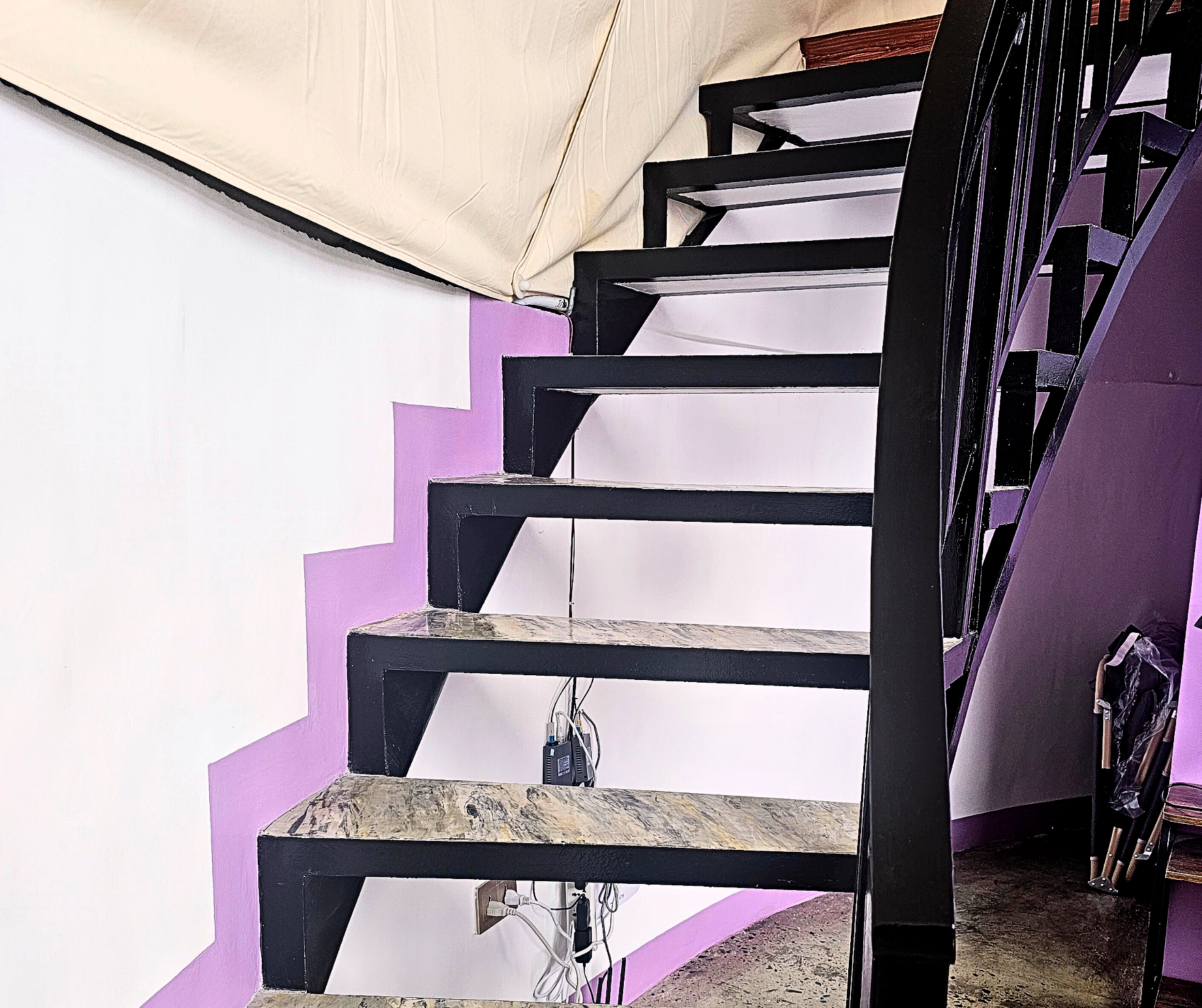 Black metal staircase with a purple accent wall and a black railing.