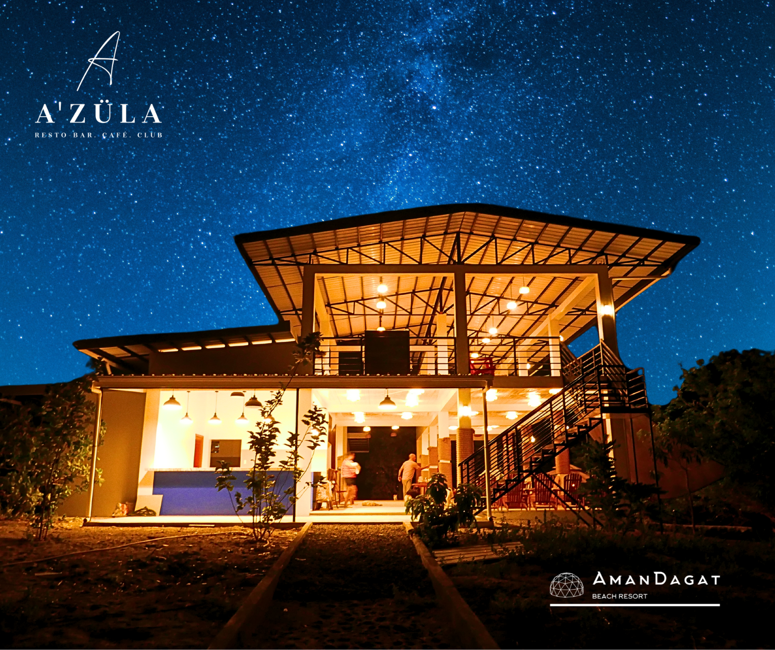 A'Zula - AmanDagat on site eclectic restaurant. A brightly lit two-story building at night, set under a vast, star-filled sky with the Milky Way visible.