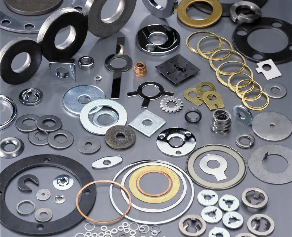 Assortment of metal washers, rings, and fasteners scattered on a surface.