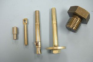 Five gold-colored metal fasteners of varying shapes and sizes arranged on a surface.