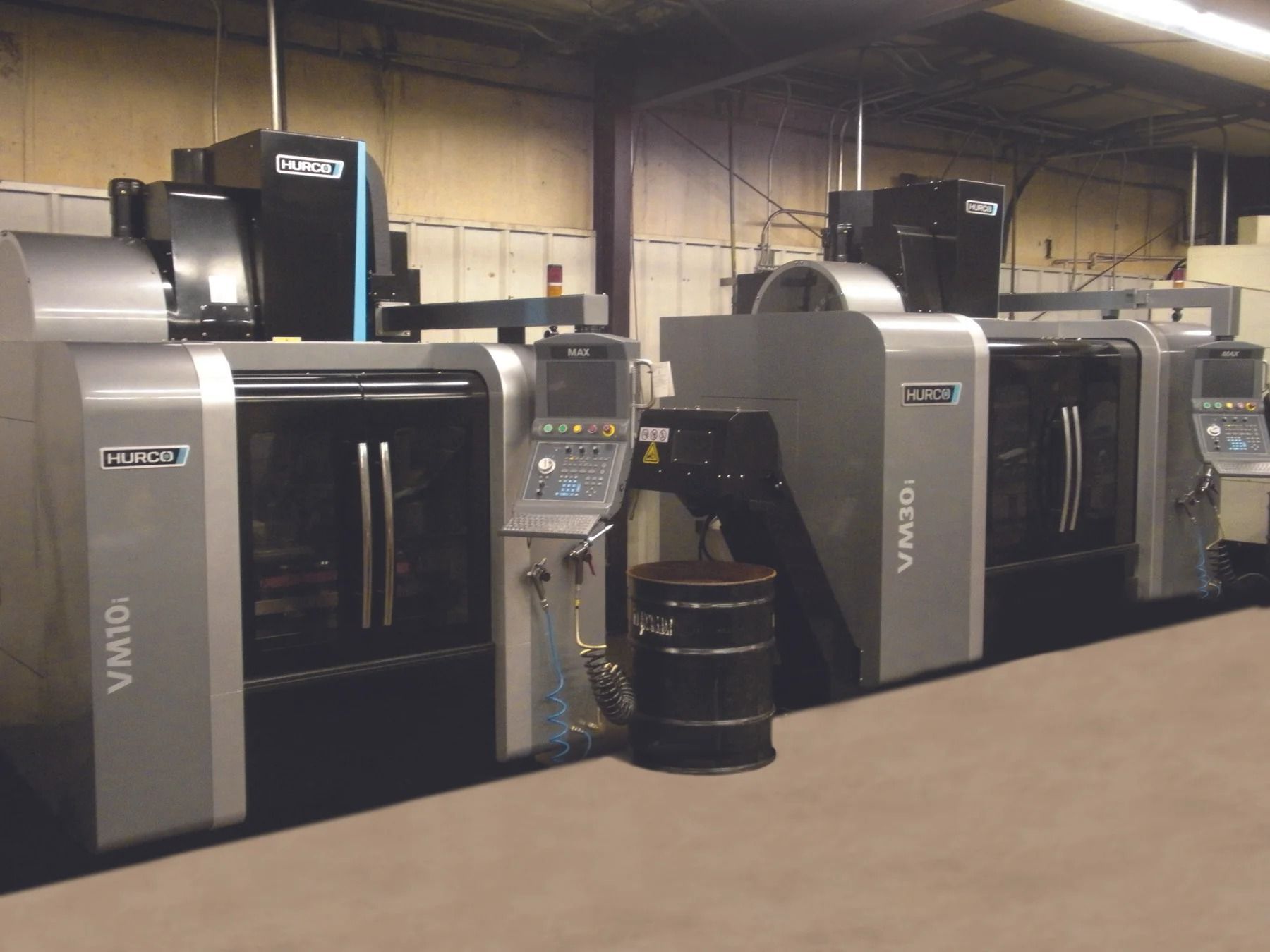 Two large gray industrial milling machines in a factory setting.