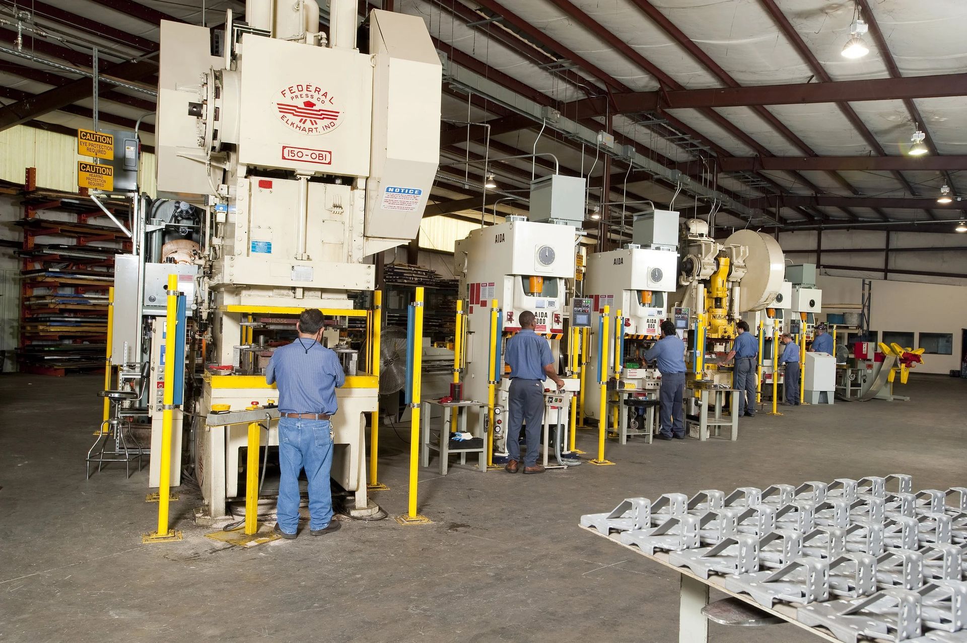 Metal stamping machines with workers in a factory setting.