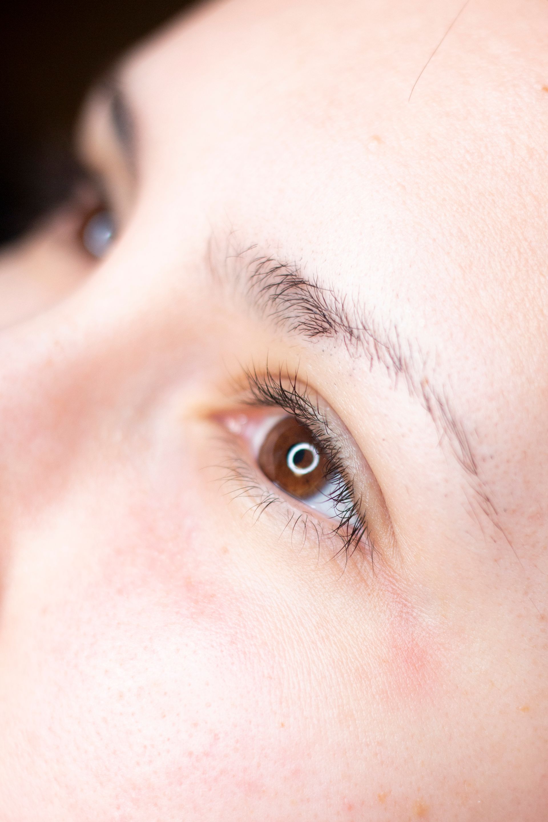 Un primo piano dell'occhio marrone di una donna con lunghe ciglia.