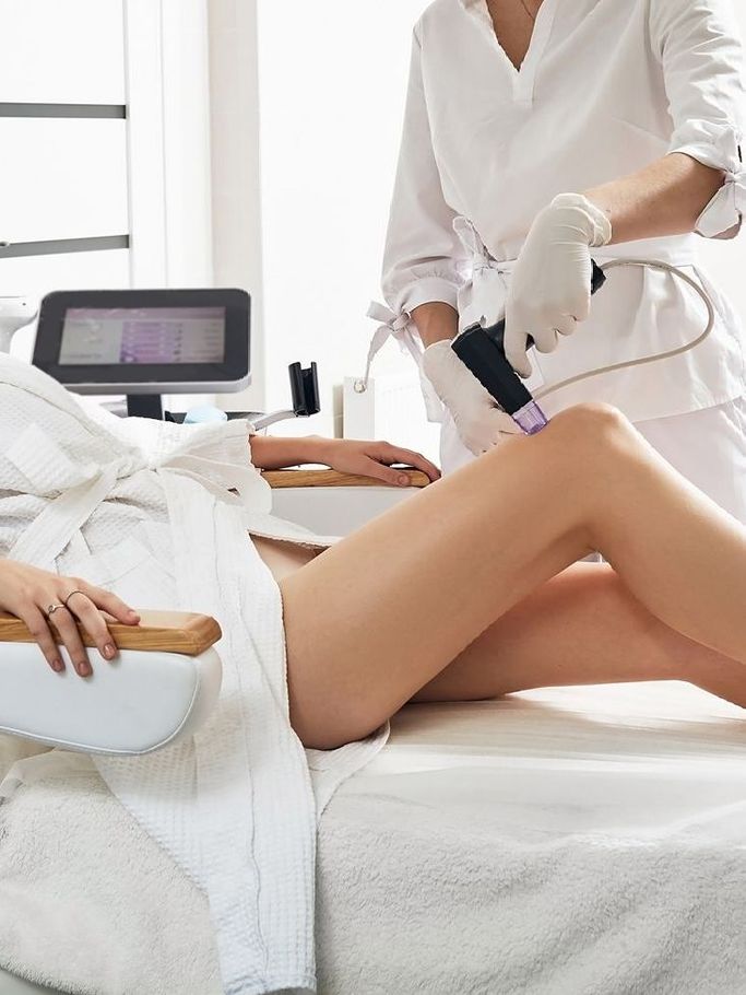 A woman is getting a laser treatment on her leg.