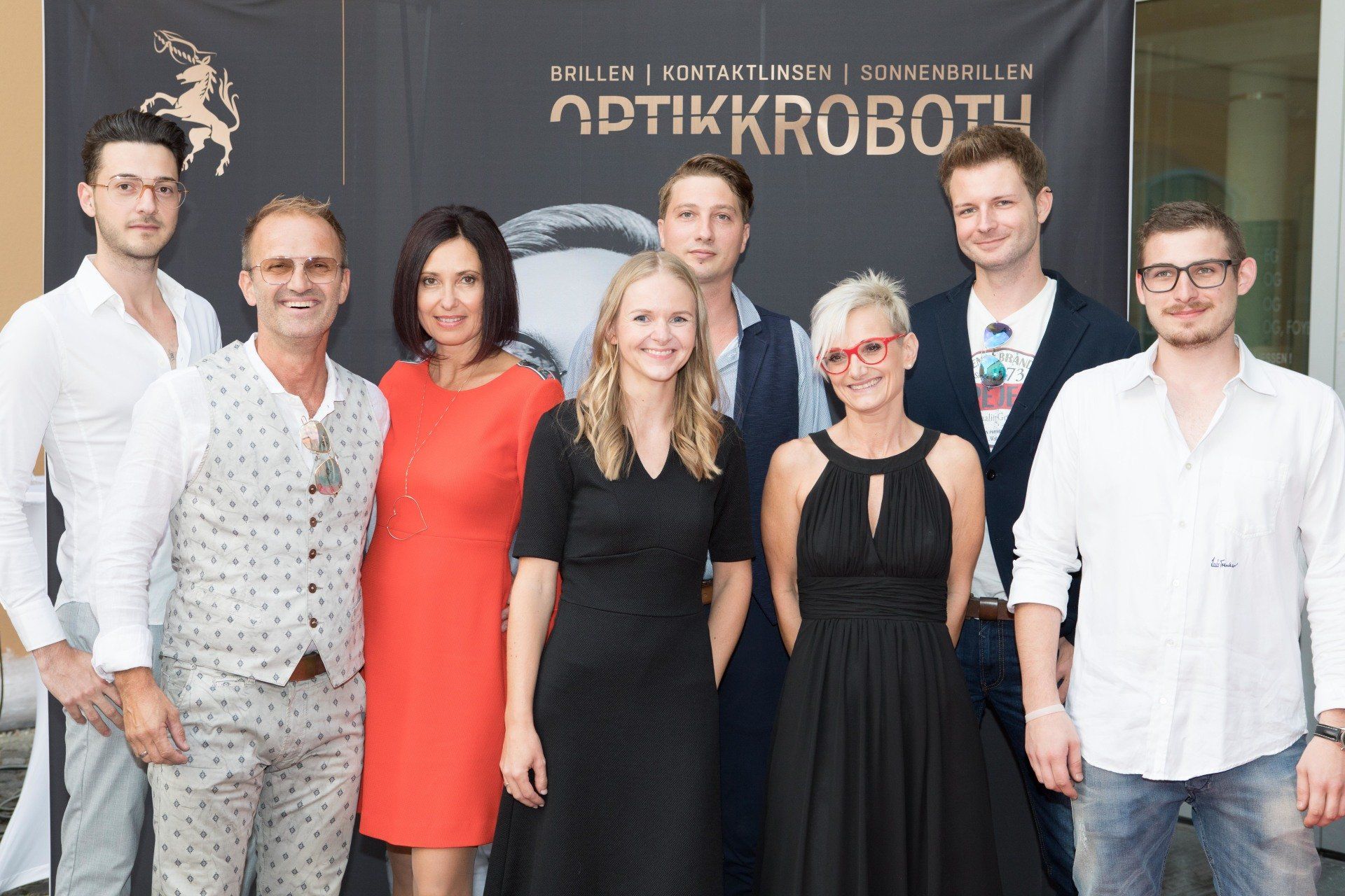 Eine Gruppe von Menschen posiert für ein Foto vor einem Schild mit der Aufschrift „Optikkrobotu“