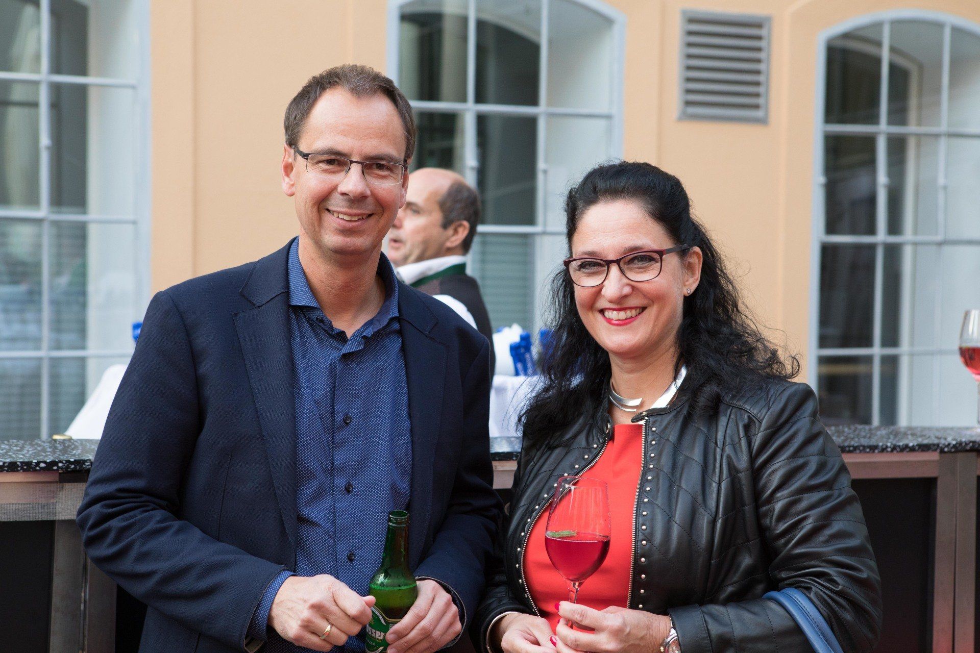 Ein Mann und eine Frau stehen nebeneinander und halten Weingläser in der Hand.
