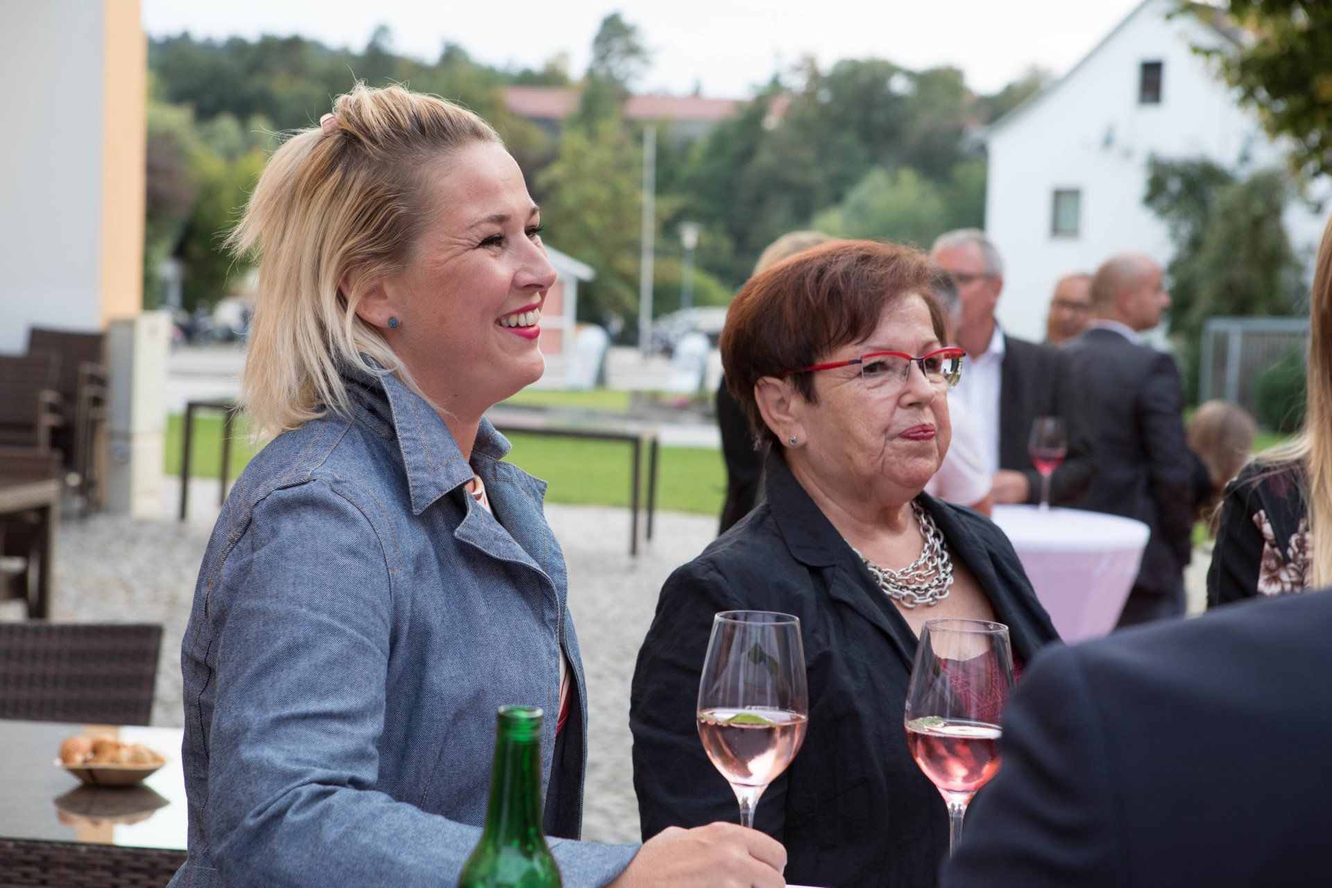 Zwei Frauen sitzen mit Weingläsern an einem Tisch.