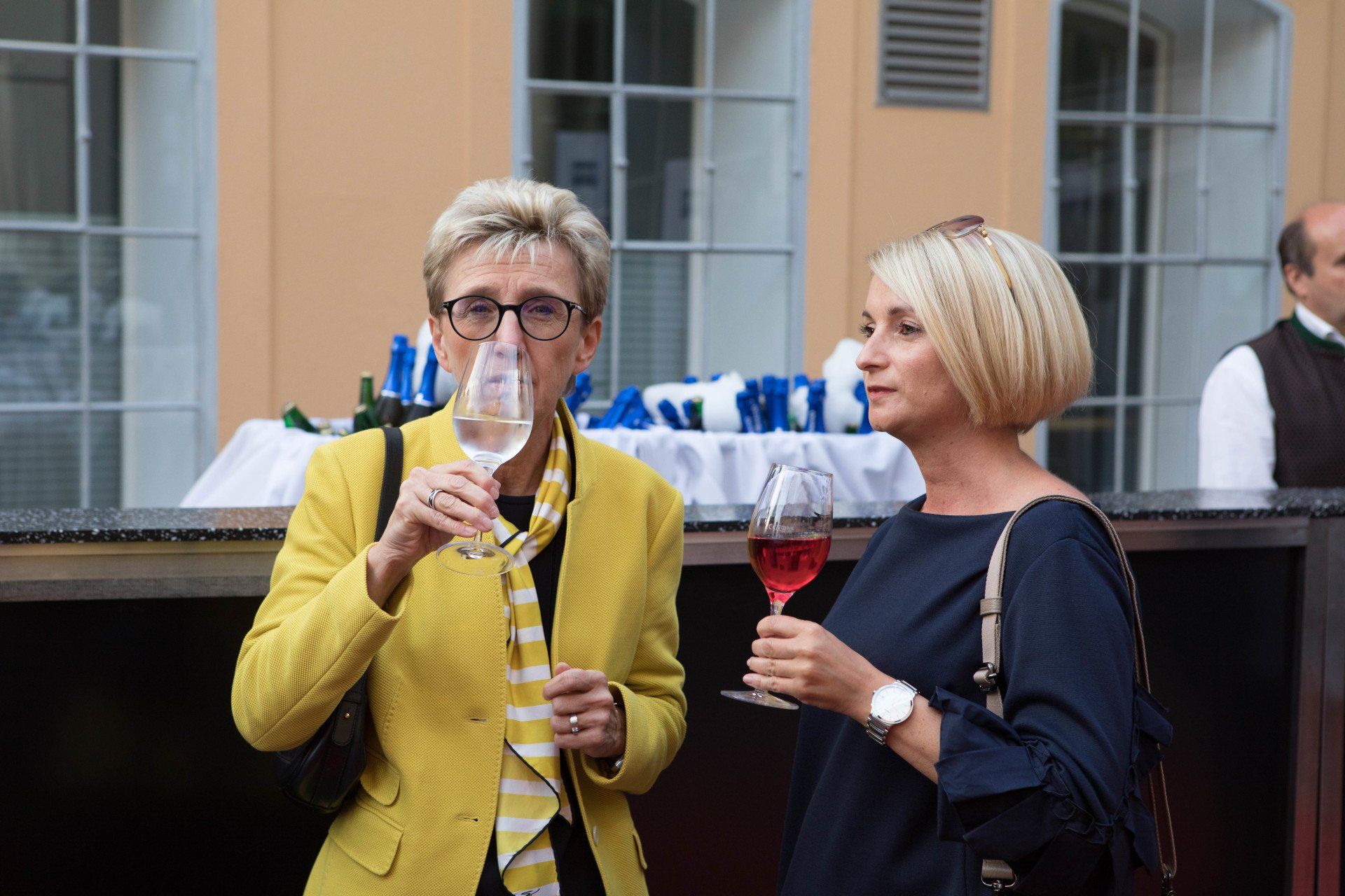 Zwei Frauen stehen nebeneinander und halten Weingläser.