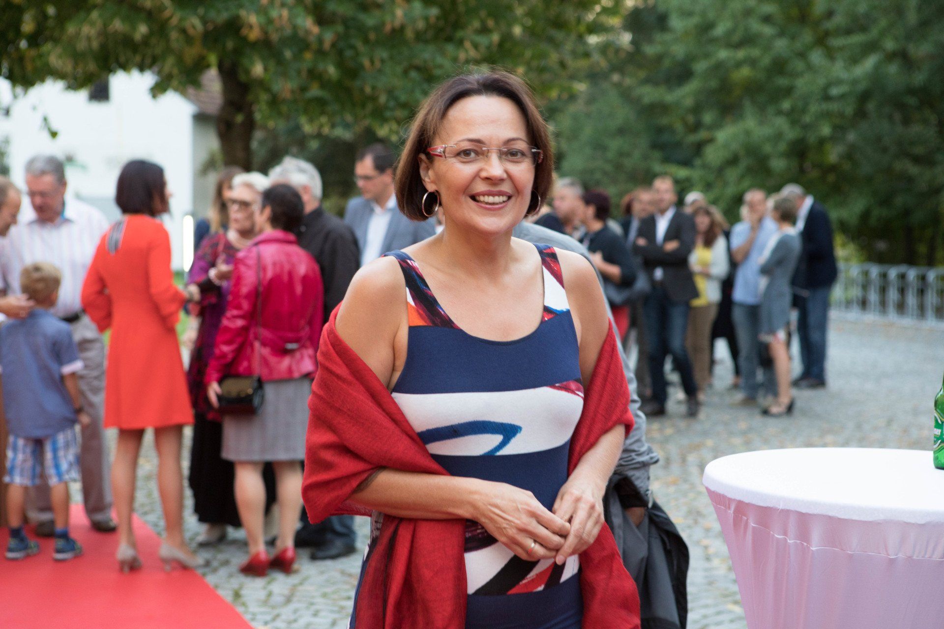 Eine Frau steht vor einer Menschenmenge auf einem roten Teppich.