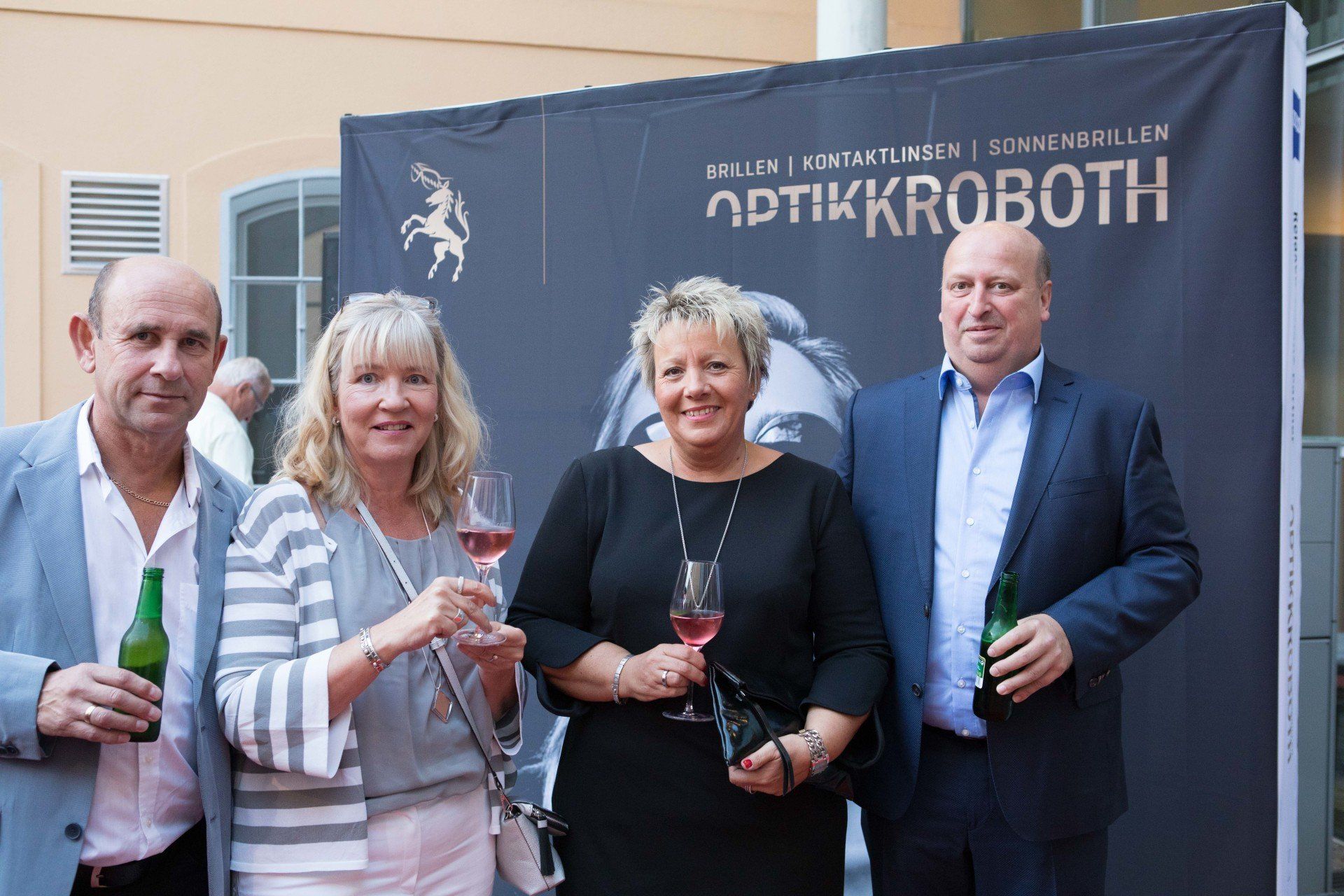 Eine Gruppe von Menschen steht vor einem Schild mit der Aufschrift „Optikkroboth“