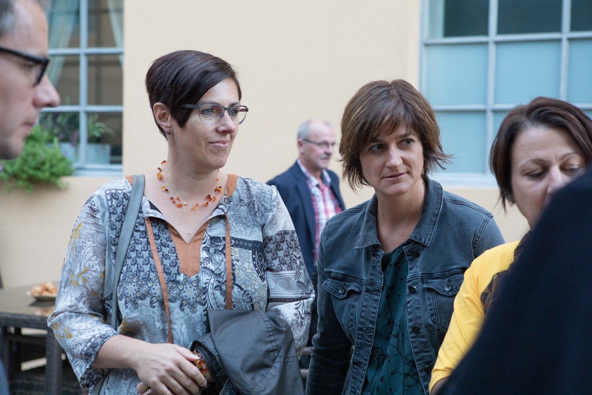 Eine Gruppe von Frauen steht vor einem Gebäude und unterhält sich.