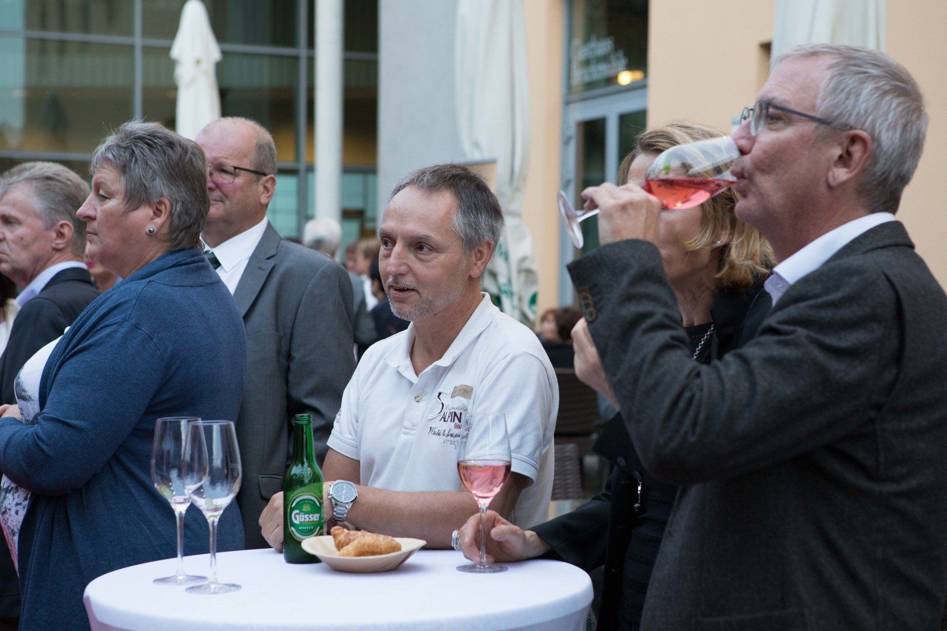 Eine Gruppe von Leuten sitzt um einen Tisch herum und trinkt Wein.