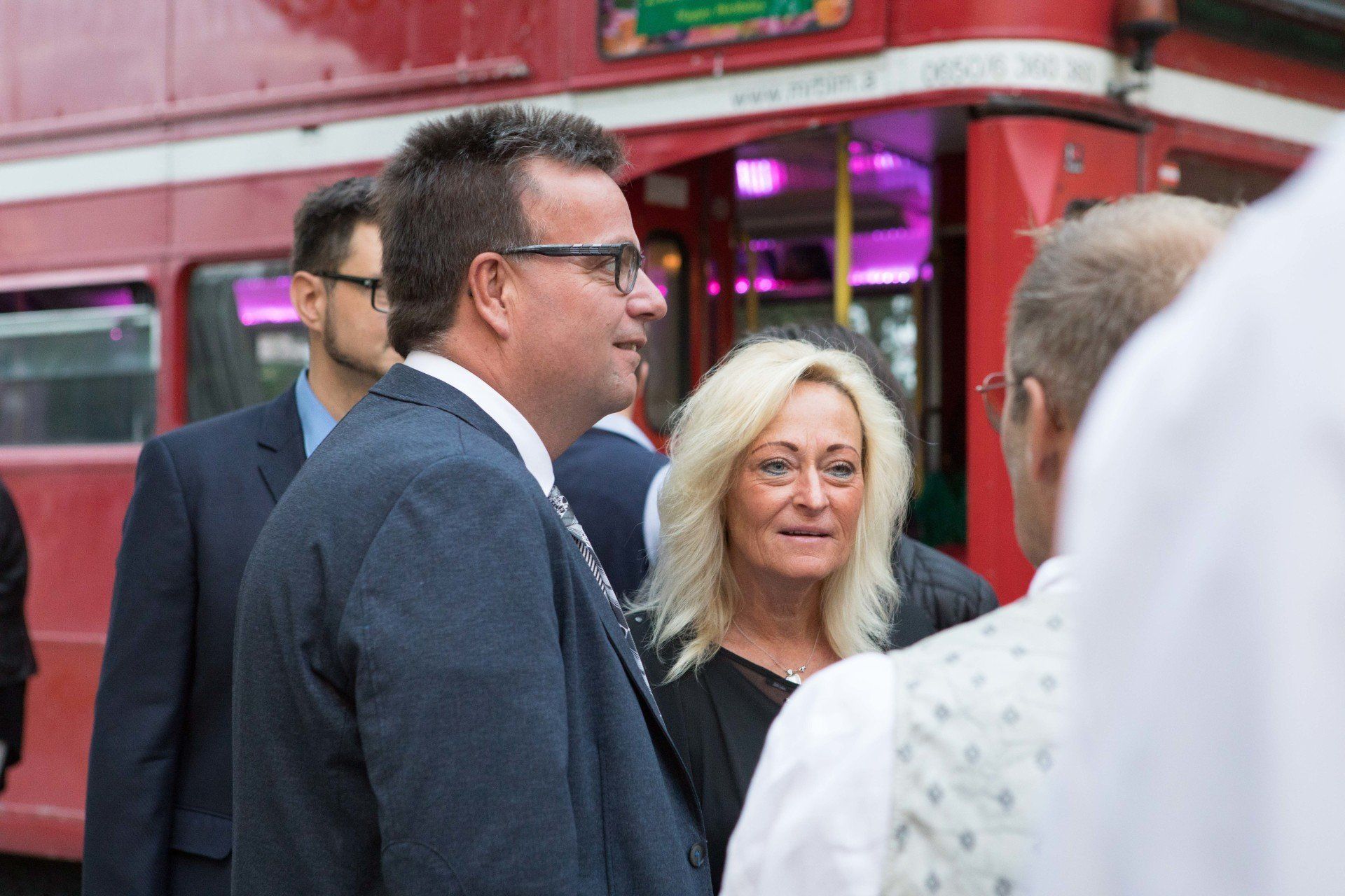 Eine Gruppe von Menschen steht vor einem roten Doppeldeckerbus.
