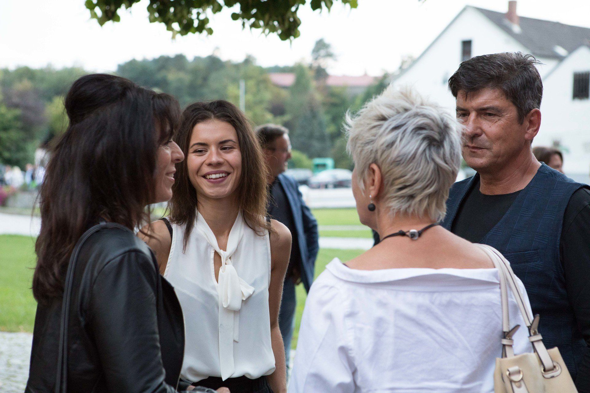 Eine Gruppe von Menschen steht in einem Park und unterhält sich.