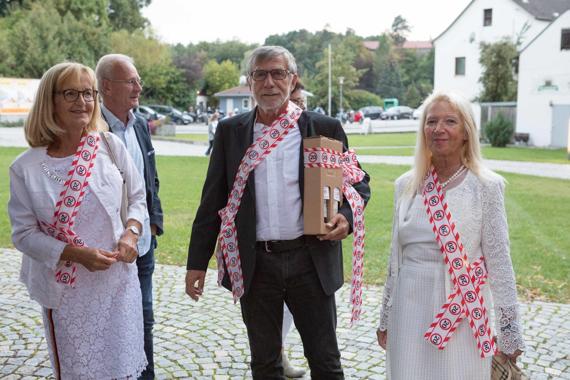 Eine Gruppe von Menschen steht nebeneinander auf einer Kopfsteinpflasterstraße.