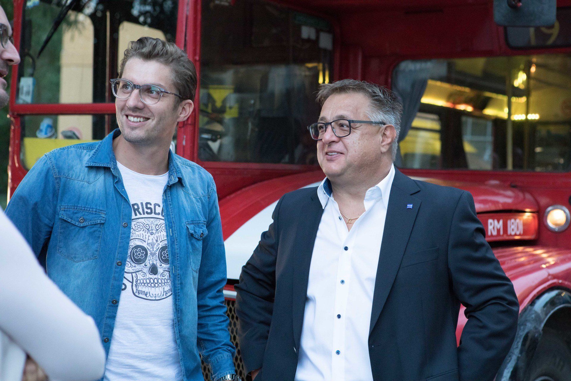 Zwei Männer stehen vor einem roten Doppeldeckerbus.