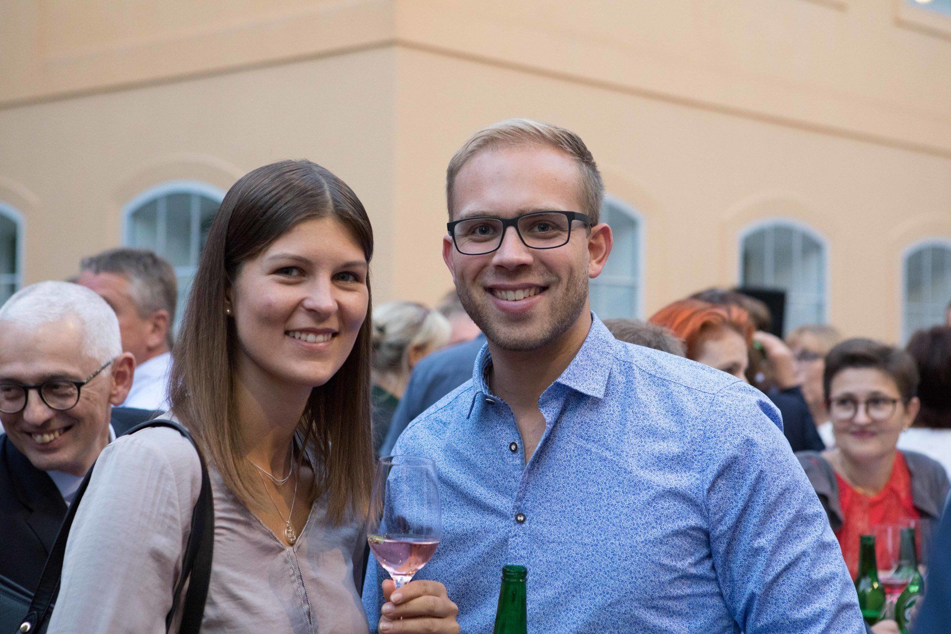 Ein Mann und eine Frau posieren mit Weingläsern in der Hand für ein Foto.