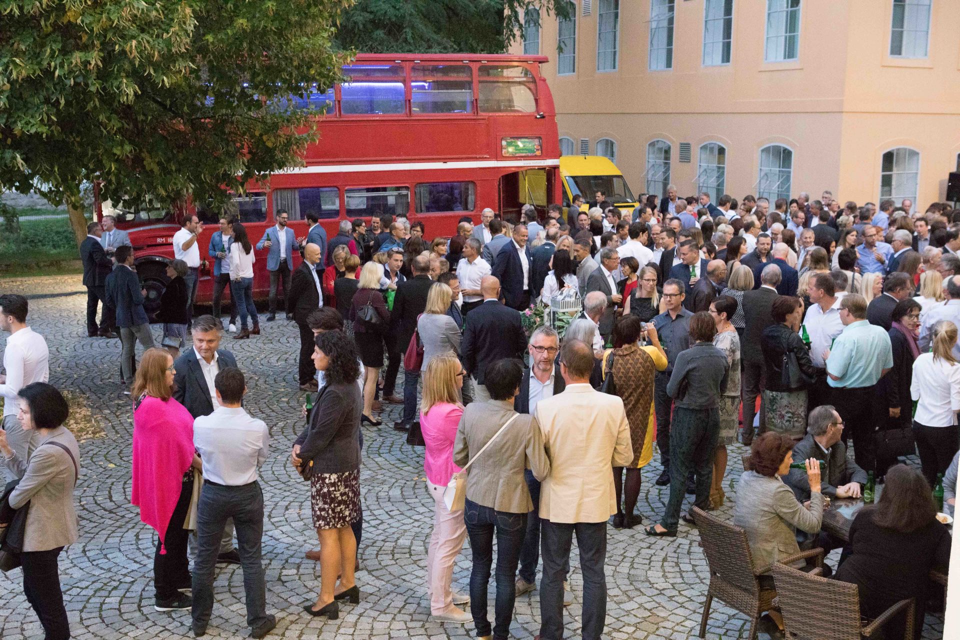 Eine große Gruppe von Menschen steht vor einem roten Doppeldeckerbus.