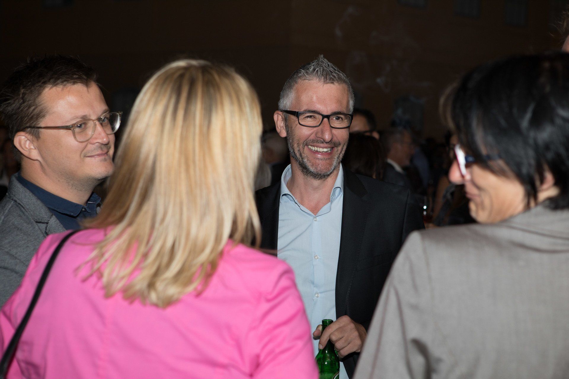 Auf einer Party steht eine Gruppe von Leuten herum und unterhält sich.