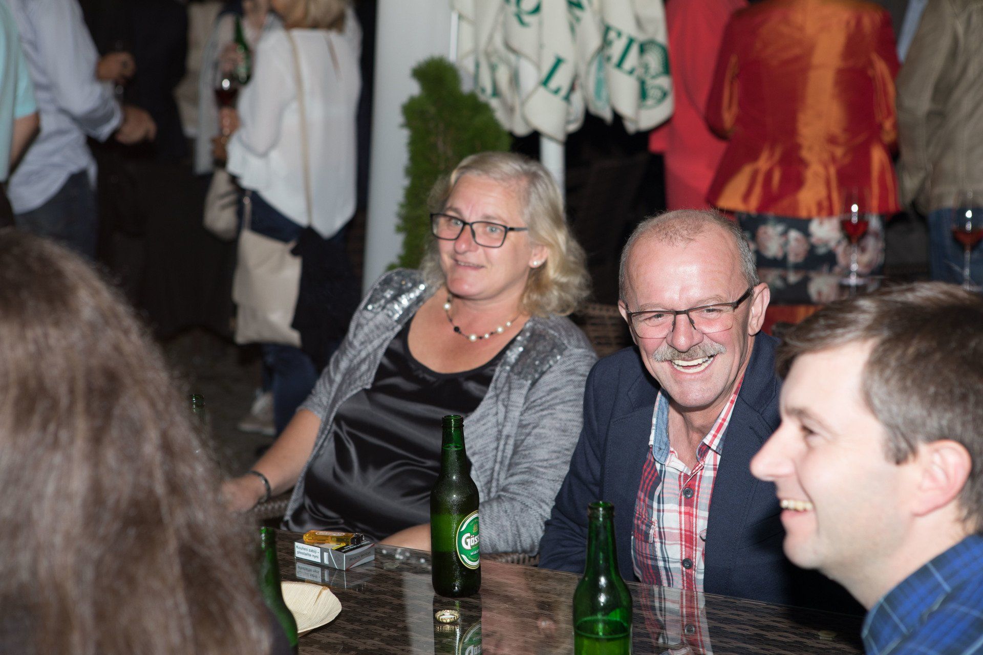 Eine Gruppe von Leuten sitzt mit Bierflaschen an einem Tisch.