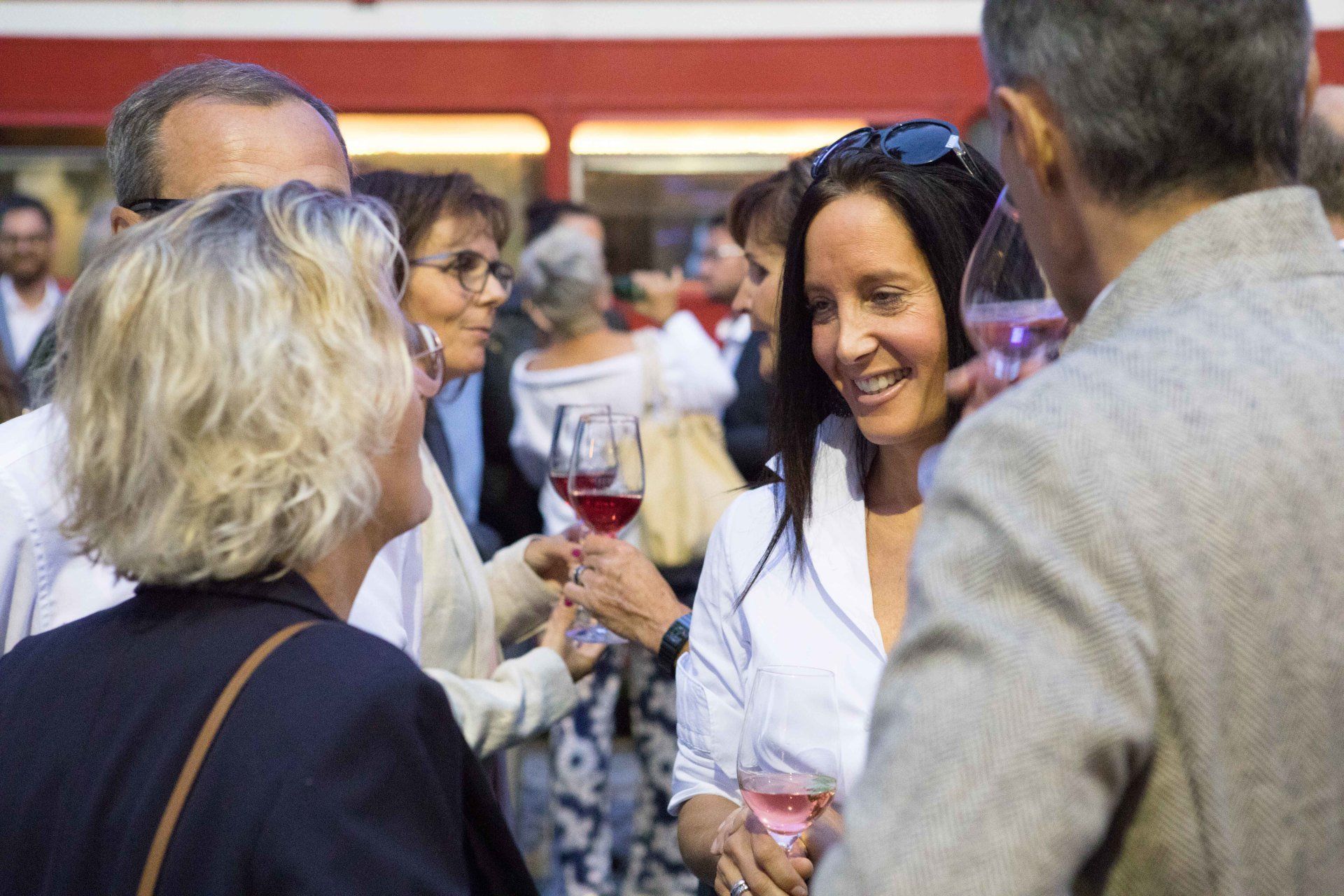 Eine Gruppe von Menschen stößt auf einer Party mit Weingläsern an.