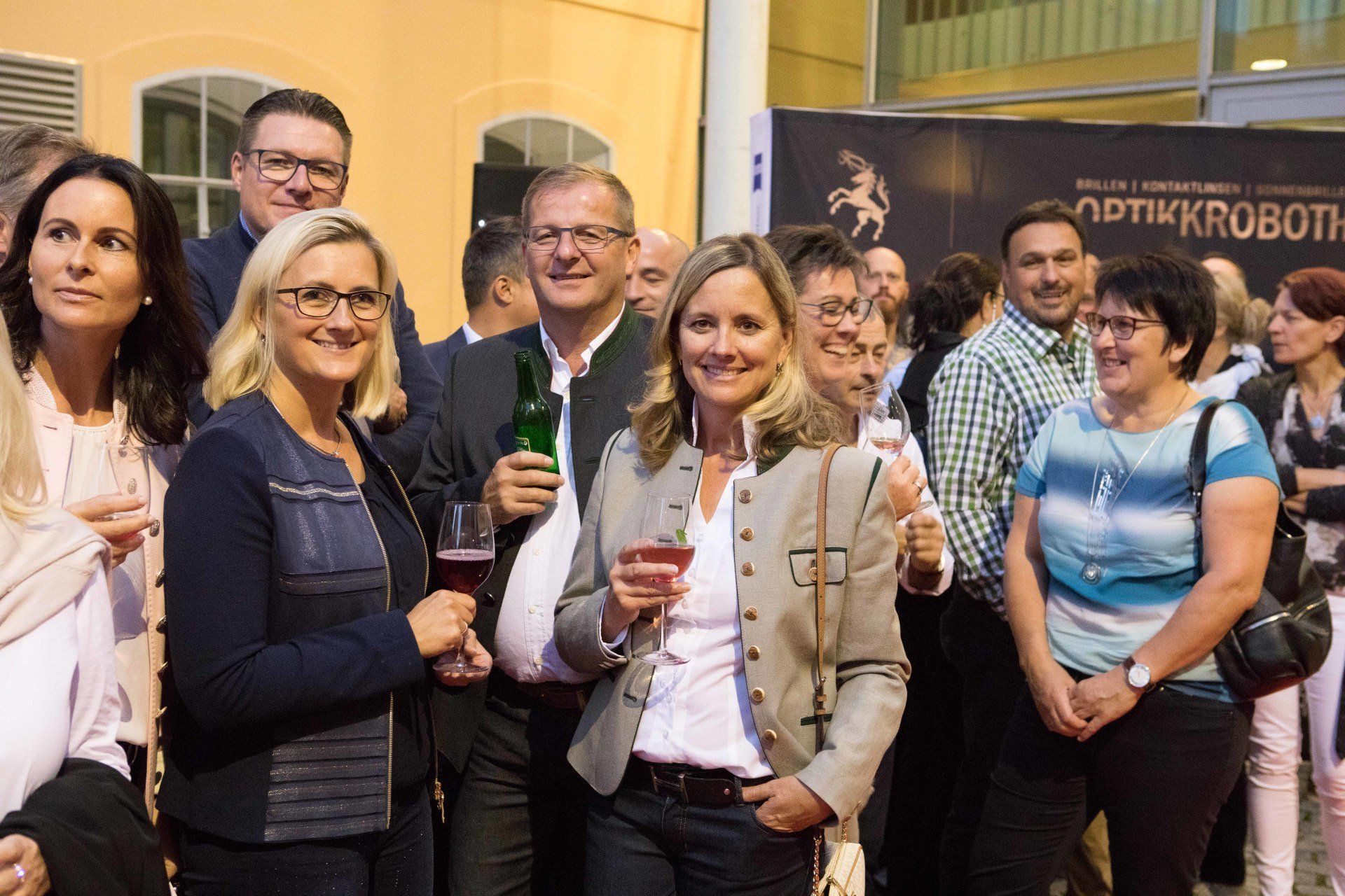 Eine Gruppe von Menschen steht nebeneinander und hält Weingläser.