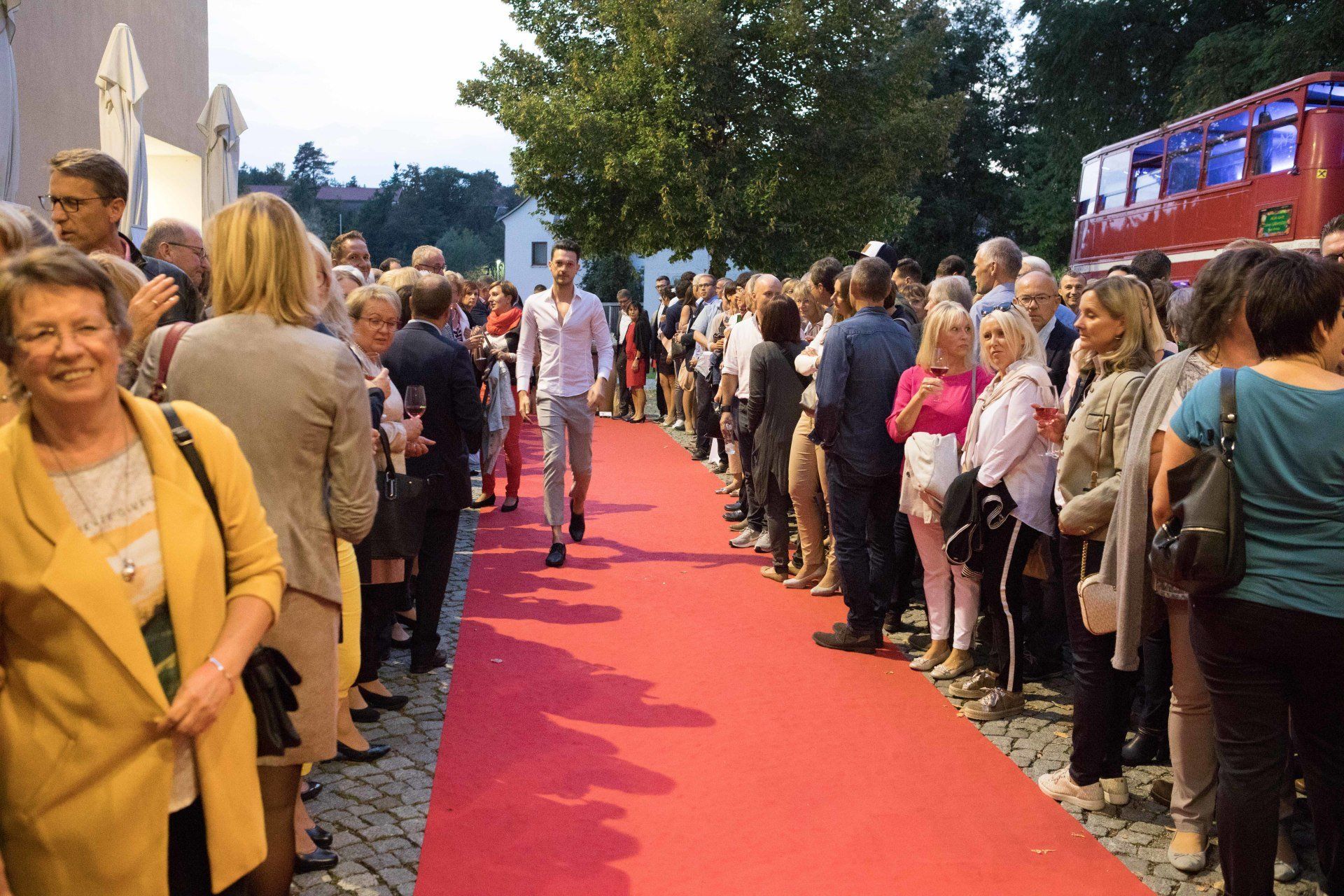 Eine große Gruppe von Menschen steht auf einem roten Teppich.