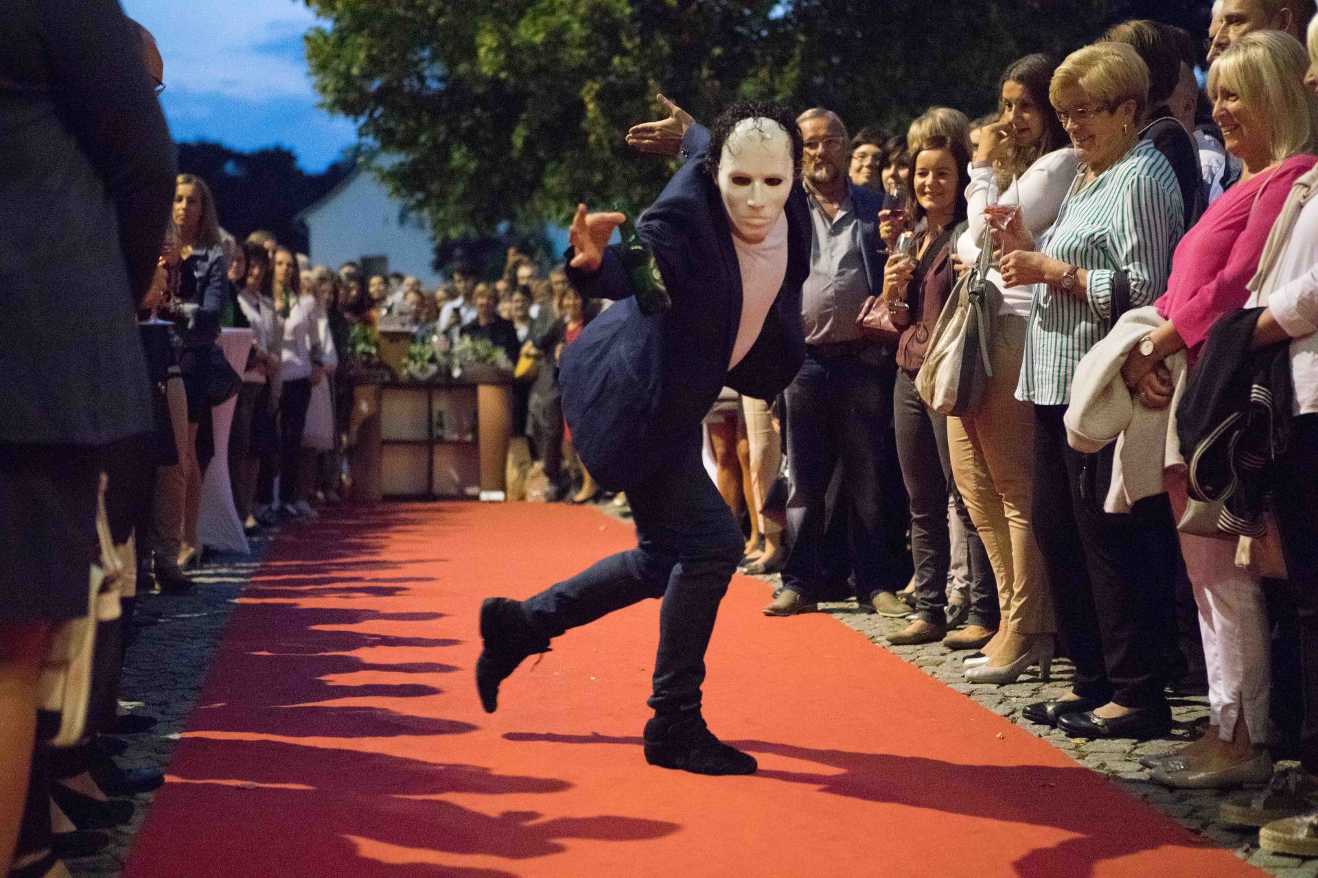 Ein Mann mit einer Maske läuft über einen roten Teppich.