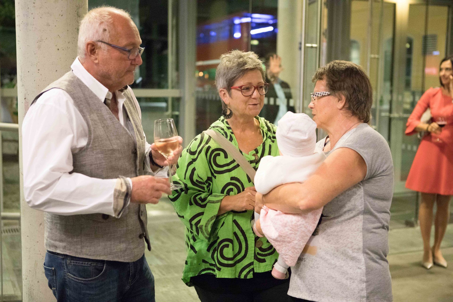 Ein Mann und zwei Frauen unterhalten sich, während eine Frau ein Baby hält.