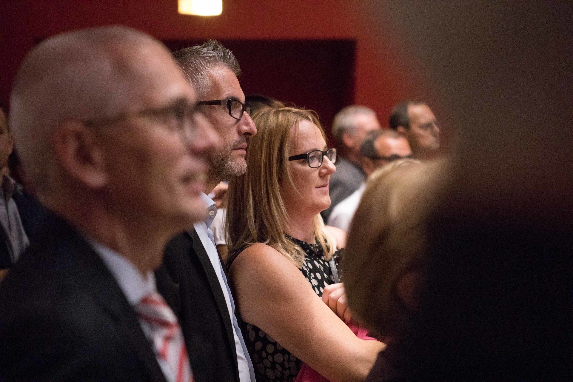 Eine Gruppe von Menschen sitzt in einem Theater und sieht sich eine Aufführung an.