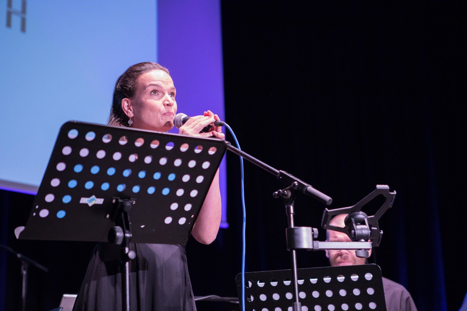 Eine Frau singt auf einer Bühne in ein Mikrofon.