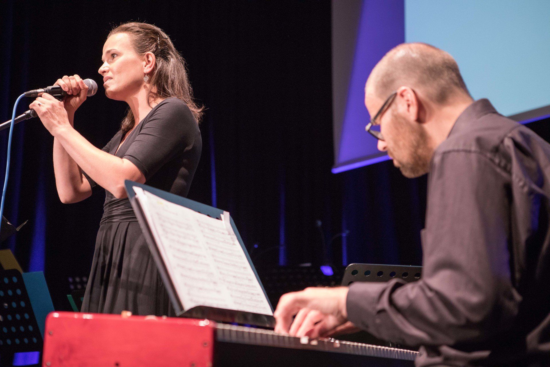 Ein Mann spielt Keyboard, während eine Frau in ein Mikrofon singt
