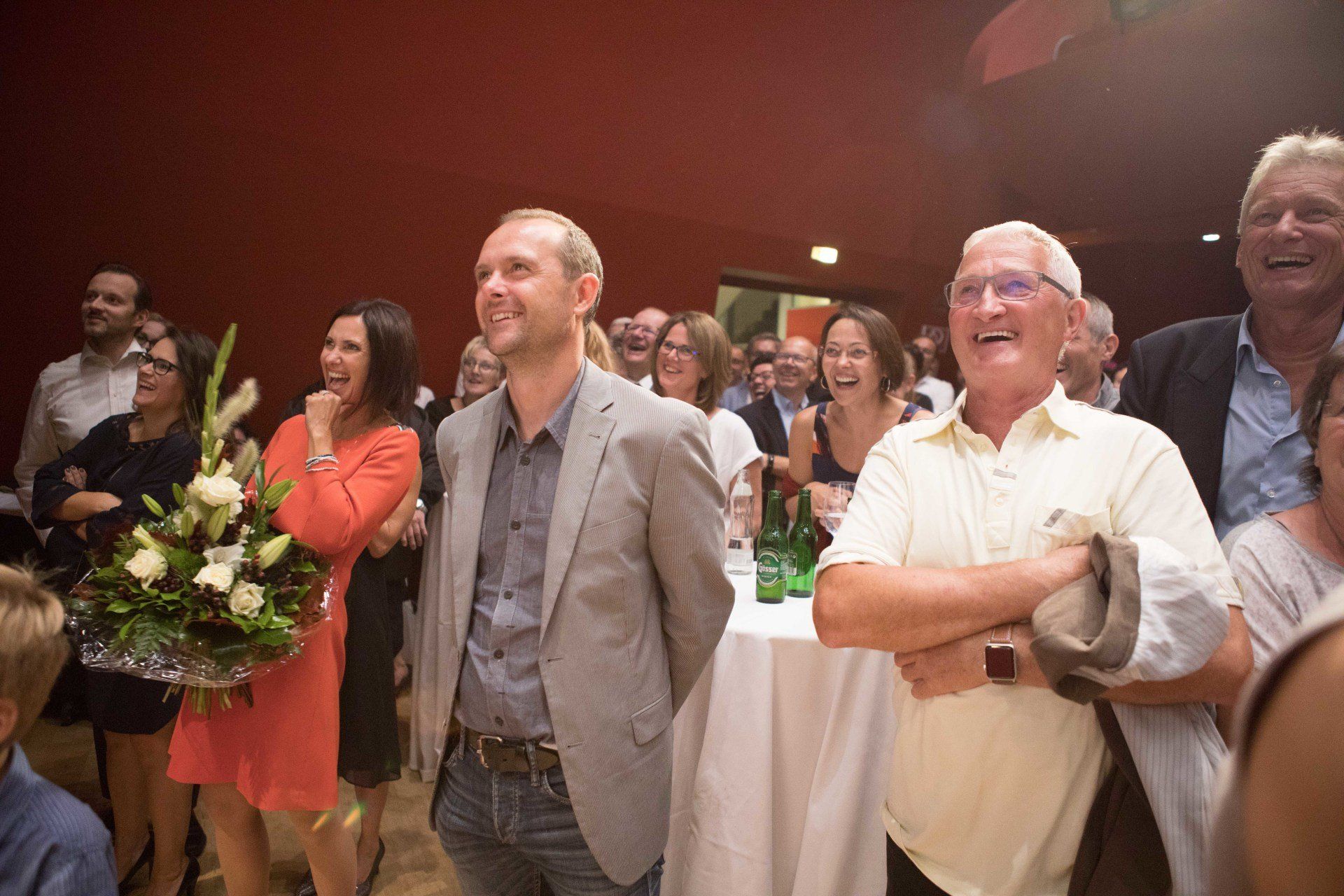 Eine Gruppe von Menschen steht in einem Raum und lacht.