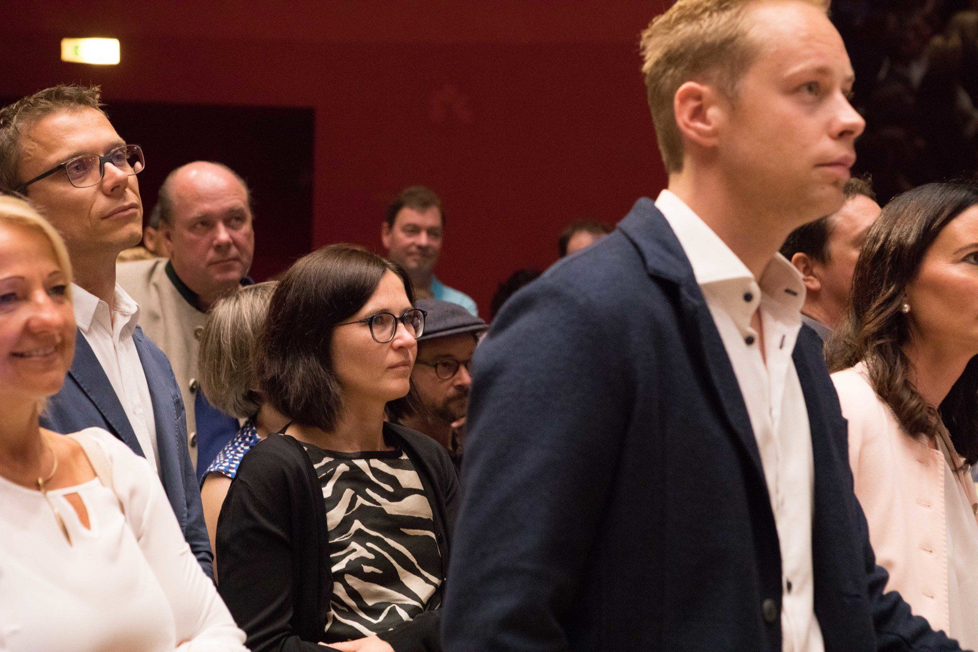 Eine Gruppe von Menschen steht in einem Raum und schaut zu etwas hinauf.