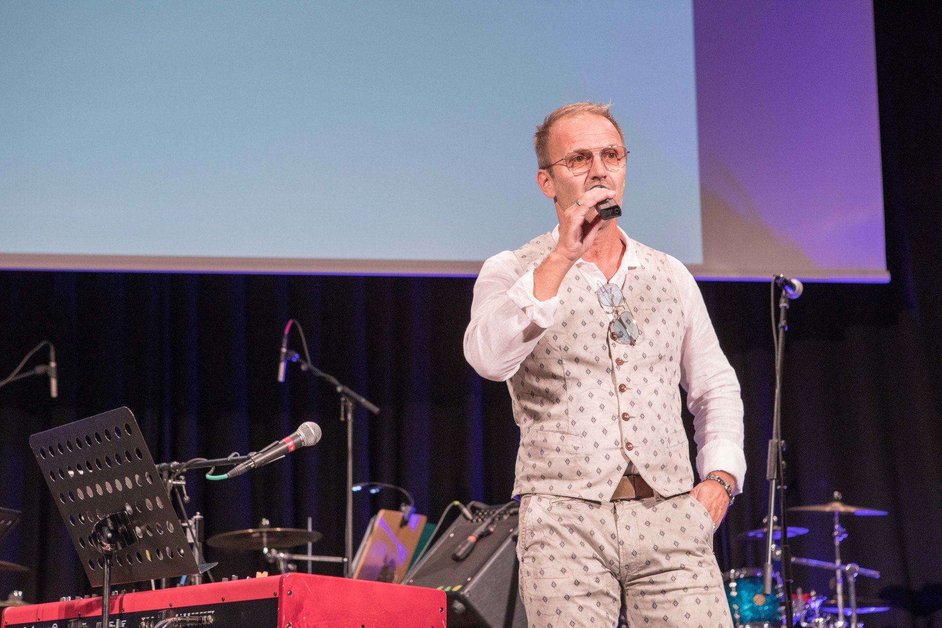 Ein Mann steht auf einer Bühne und hält ein Mikrofon.