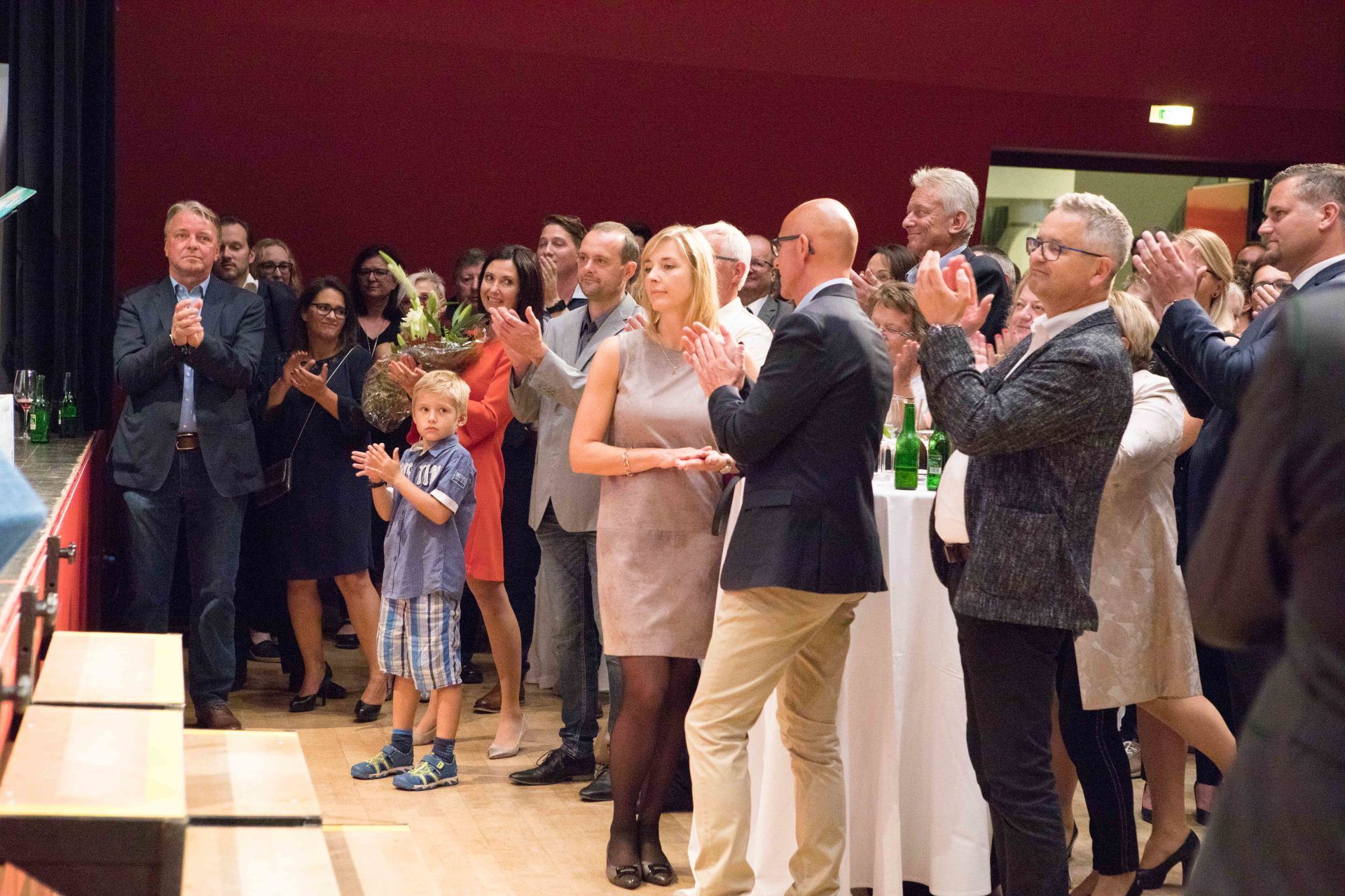 Eine Gruppe von Menschen steht in einem Raum und applaudiert.