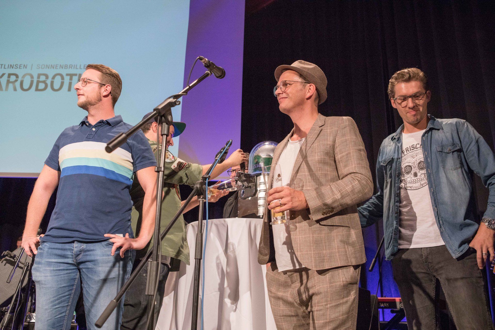Eine Gruppe Männer steht auf einer Bühne vor einem Mikrofon.