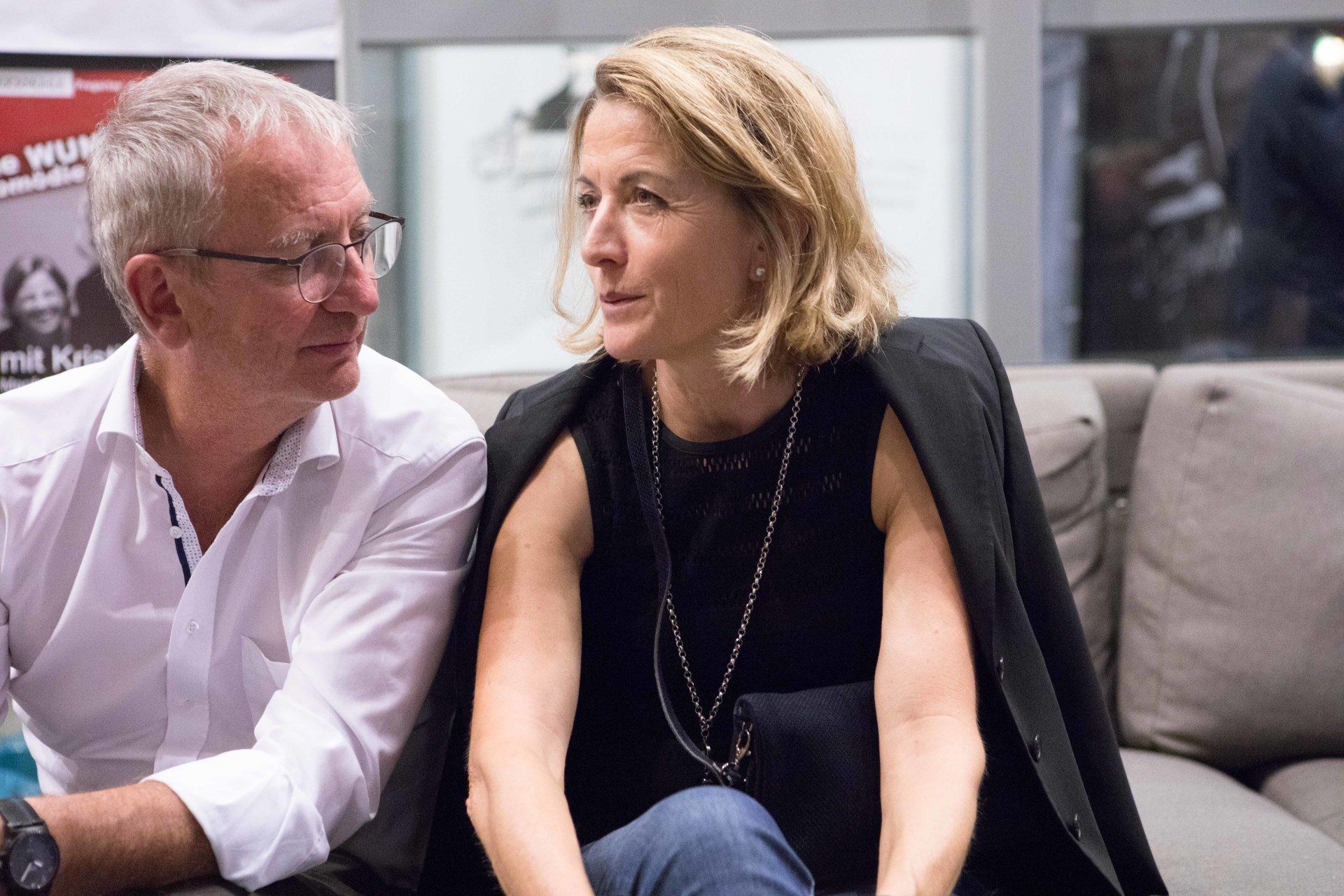 Ein Mann und eine Frau sitzen auf einem Sofa und unterhalten sich.