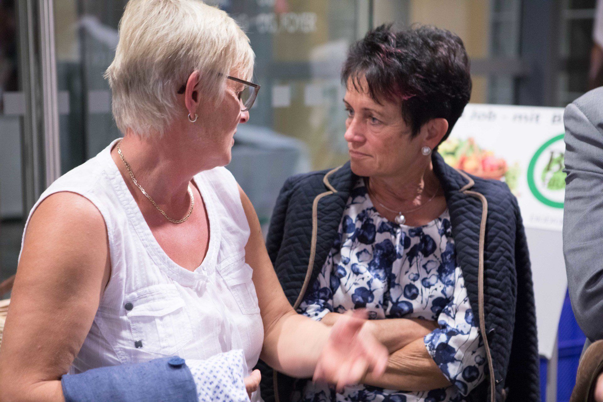 Zwei Frauen unterhalten sich in einem Raum miteinander.