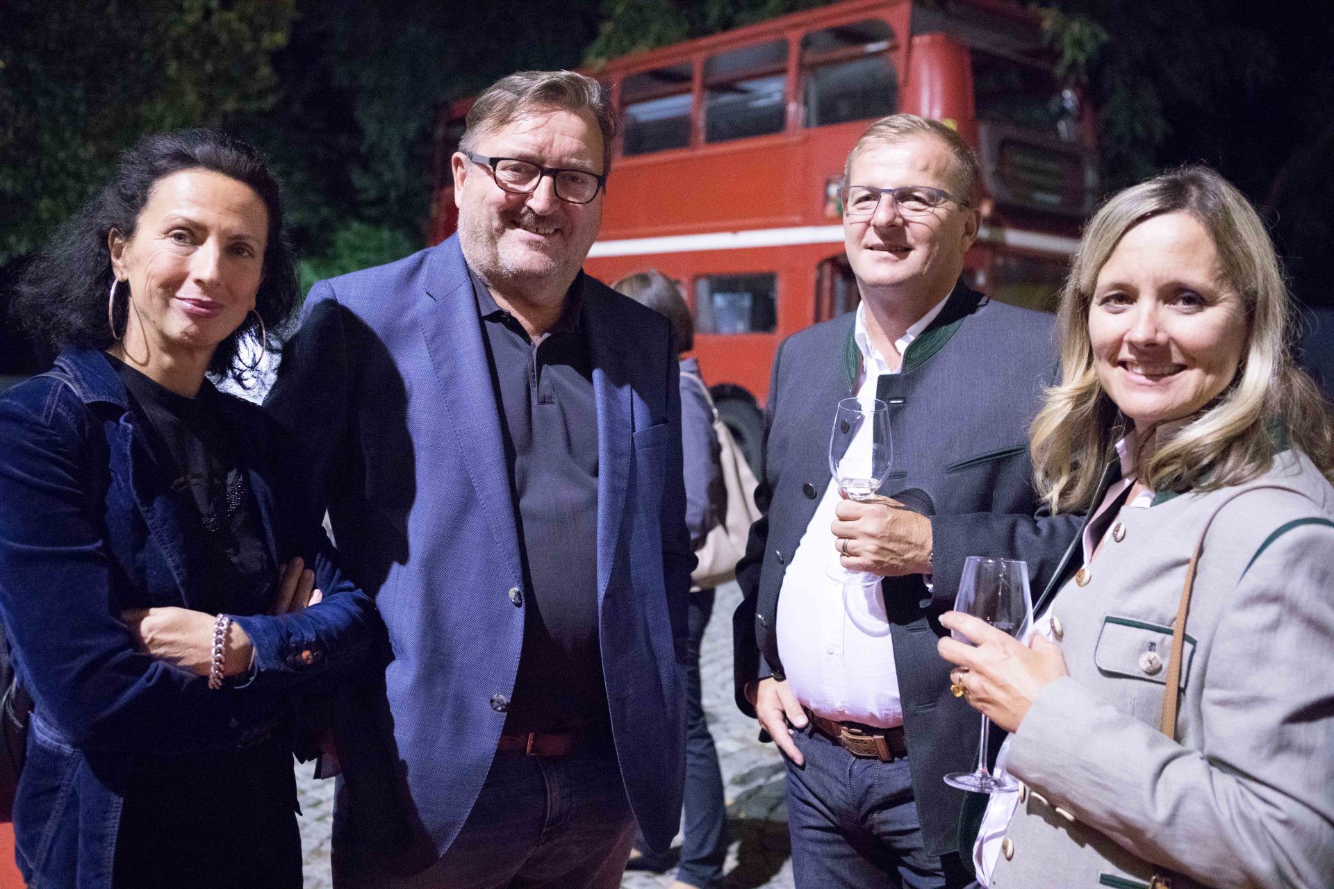 Eine Gruppe von Menschen posiert für ein Foto vor einem roten Doppeldeckerbus.