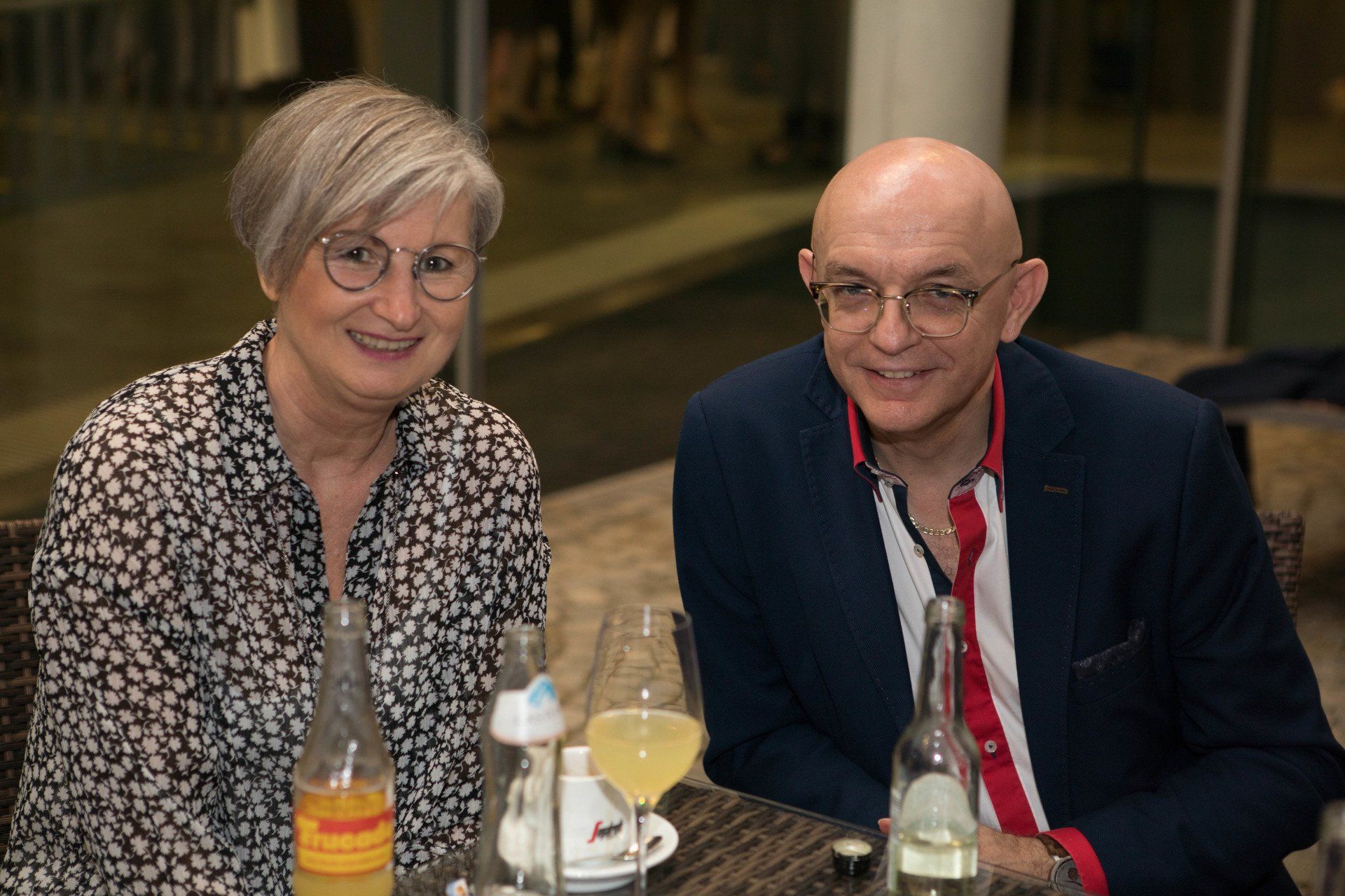 Ein Mann und eine Frau sitzen mit Weingläsern an einem Tisch.